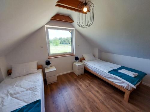 a attic room with two beds and a window at Ahoj Siemiany in Siemiany