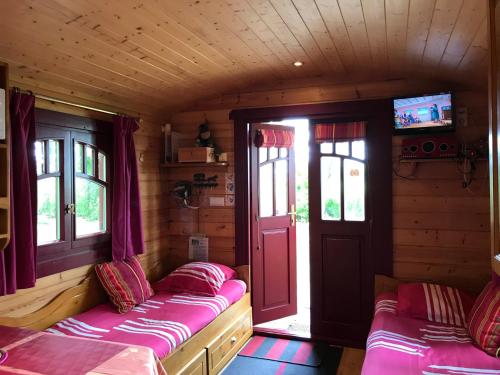 a room with two beds and a door and windows at Gite Insolite "La Roulotte des Elfes", Au Milieu de Nulle Part in Outines