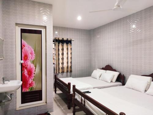 a bedroom with two beds and a sink and a mirror at Sree Shanmuga Residency in Vagamon