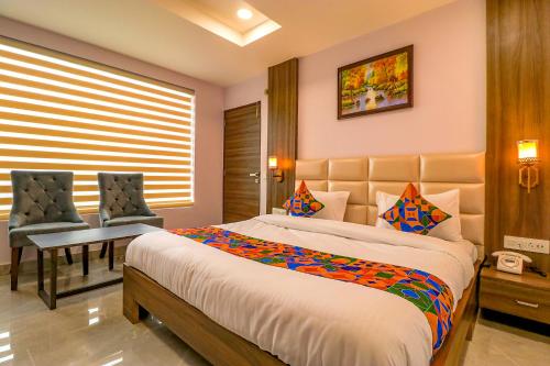 a bedroom with a large bed and two chairs at FabHotel Prime K9 Regency in Jalandhar