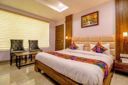 a bedroom with a large bed and two chairs at FabHotel Prime K9 Regency in Jalandhar