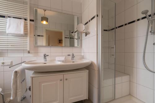 a white bathroom with a sink and a shower at Ferienwohnung Seeschwalbe in Südstrand