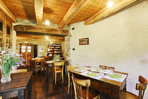 comedor con techos de madera, mesas y sillas en Locanda Al Torch - Ristorante e Camere, en Stroppo