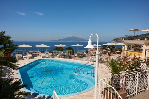 a swimming pool with chairs and umbrellas on a resort at Grand Hotel de la Ville in Sorrento