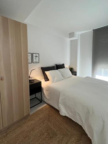 a bedroom with a large white bed and a side table at Topdown Apartments in Hospitalet de Llobregat