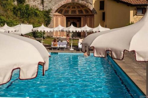 a swimming pool with blue water and white umbrellas at Hole 1 - Cozy place on Castelgandolfo Golf Course in Castel Gandolfo