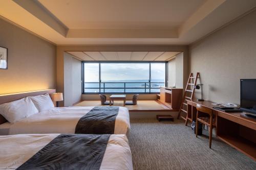a hotel room with two beds and a large window at Infinito Hotel and Spa in Shirahama