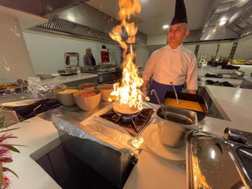 a chef is preparing food in a kitchen with flames at Riviera Zen Hotel Adult Only in Alanya