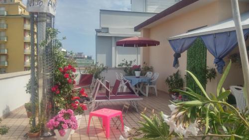 einen Balkon mit einem Tisch, Stühlen und Blumen in der Unterkunft Guest House Attico Della Vittoria in Gabicce Mare