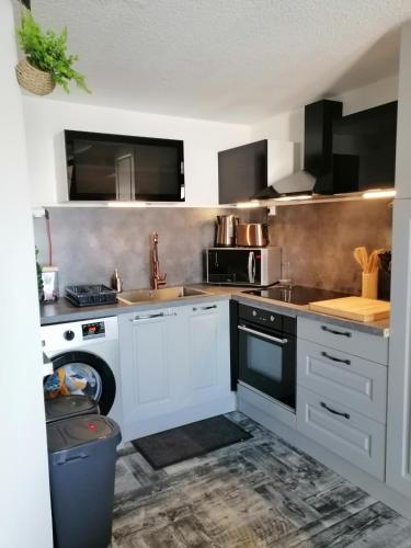 La cuisine est équipée de placards blancs et d'un lave-vaisselle. dans l'établissement Au Grain De Sel..., à Gruissan