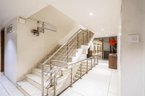 a staircase in a home with white walls and white tile floors at Hotel Bhabha in Rajkot