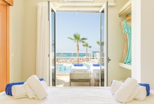 a bedroom with a bed and a view of the beach at Parthenis Beach, Suites by the Sea in Malia
