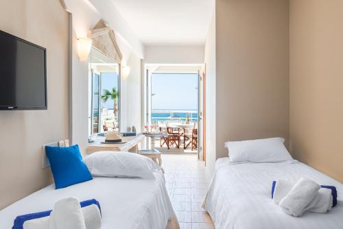 two beds in a room with a view of the ocean at Parthenis Beach, Suites by the Sea in Malia