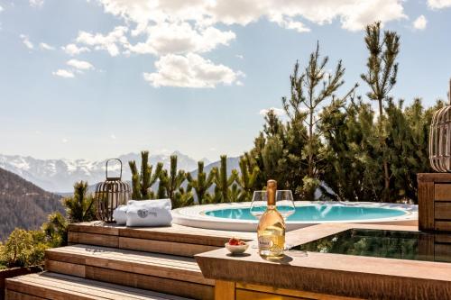 una botella de vino sentada en una mesa junto a la piscina en Cocoon Deluxe - Luxury Chalet, en Chamois