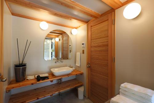 a bathroom with a sink and a mirror at 泊まれるアートミュージアム 琉球ヴィラ in Tatsugo