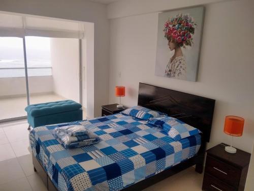 ein Schlafzimmer mit einem blauen und weißen Bett und einem Stuhl in der Unterkunft Departamento en Punta Hermosa con Vista al Mar in Punta Hermosa