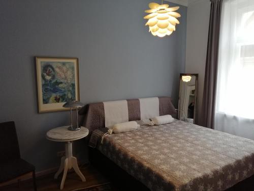 a bedroom with a bed and a table and a chandelier at Alberthof Zittau in Zittau