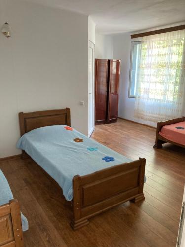 a bedroom with a bed and a wooden floor at Guest House Maxim in Makhinjauri