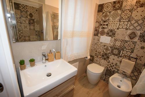 a bathroom with a white sink and a toilet at LOFT LUNGOMARE vista MARE e MONTI in Àrbatax