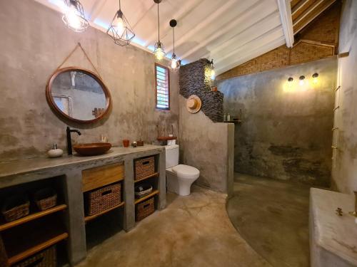 ein Badezimmer mit einem Waschbecken, einem WC und einem Spiegel in der Unterkunft The Beach Shack in Gili Air