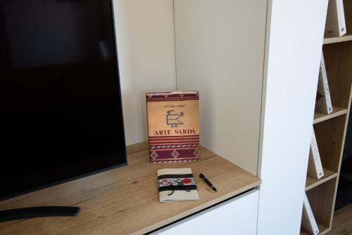 a box and a pen on a shelf next to a tv at LOFT LUNGOMARE vista MARE e MONTI in Àrbatax