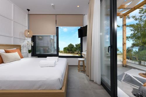 a bedroom with a large bed and a large window at NiSea Beach Apartments in Prinos