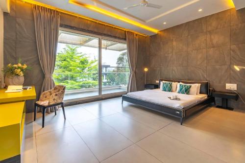 a bedroom with a bed and a desk and a window at StayVista's Verde Villa with Private Pool, Games Room & Terrace in Lonavala