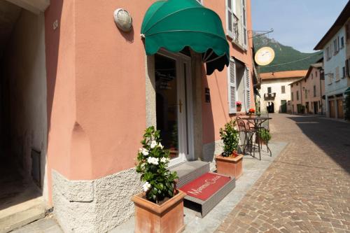 un bâtiment rose avec des plantes en pot dans une rue dans l'établissement Mamma Ciccia, à Mandello del Lario