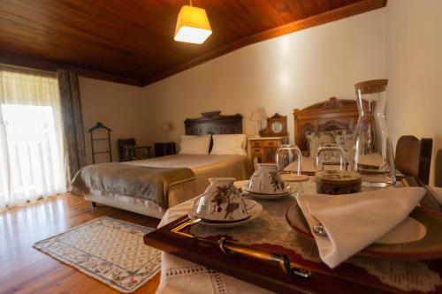 a bedroom with a bed and a table with dishes at Quintal De Alem Do Ribeiro-Turismo Rural in Lousã