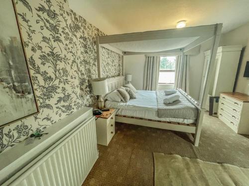 a bedroom with a white bed and white walls at Carreg Bran in Llanfairpwllgwyngyll