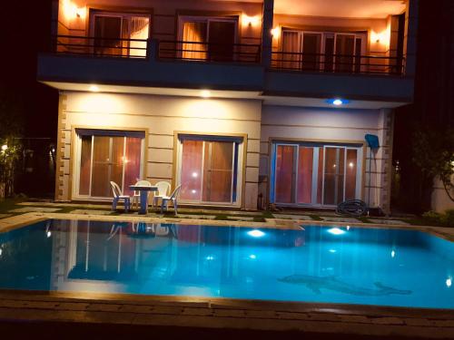 a swimming pool in front of a house at night at Lovely Villa 5- bedroom with Overflow Pool with Nice Garden at Green Oasis Resort in Alexandria