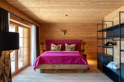 a bedroom with a pink bed and a wooden ceiling at Mountain Chalet R in Berwang