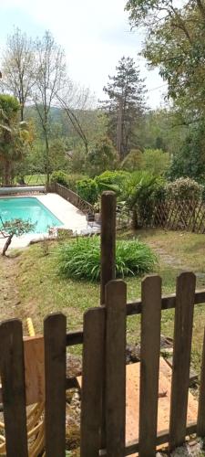 a wooden fence in front of a swimming pool at Les Gîtes du Hameau avec piscine in Castelnau-sur-Gupie