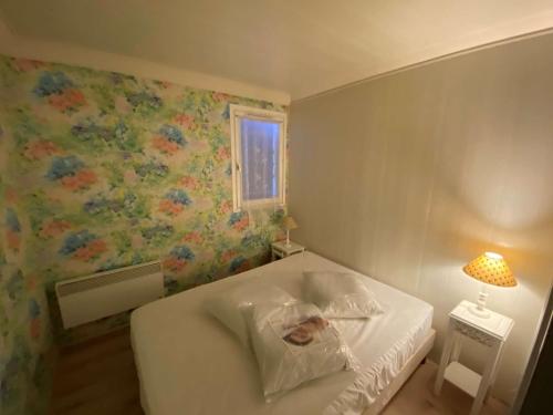 - une chambre avec un lit blanc et un mur fleuri dans l'établissement 2 pièces avec terrasse et parking à Port Camargue - 6 couchages, appontement inclus - FR-1-250-231, au Grau-du-Roi