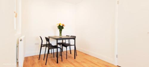 a table with chairs and a vase with flowers on it at Phlox Garden in Sutton