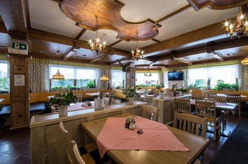 ein Restaurant mit Holztischen, Stühlen und Fenstern in der Unterkunft Gasthof Hauserwirt in Wörgl