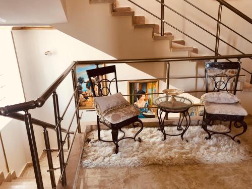a room with chairs and a table and stairs at Lovely Villa 5- bedroom with Overflow Pool with Nice Garden at Green Oasis Resort in Alexandria