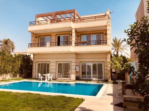 a villa with a swimming pool in front of a house at Lovely Villa 5- bedroom with Overflow Pool with Nice Garden at Green Oasis Resort in Alexandria