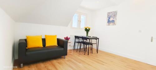 a living room with a couch and a table with yellow pillows at Phlox Garden in Sutton