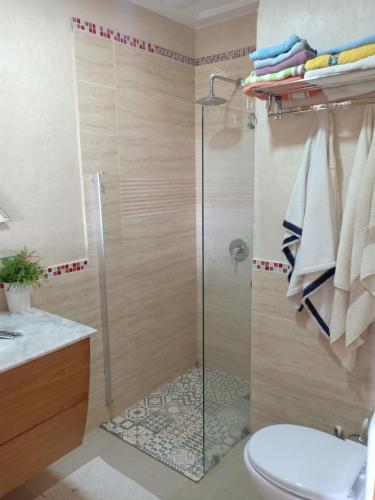 uma casa de banho com um chuveiro, um WC e um lavatório. em bel appart dans une résidence avec piscine, à 750m de la plage. Confort garanti. em Saidia 