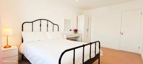 a white bedroom with a large bed and a desk at Phlox Garden in Sutton