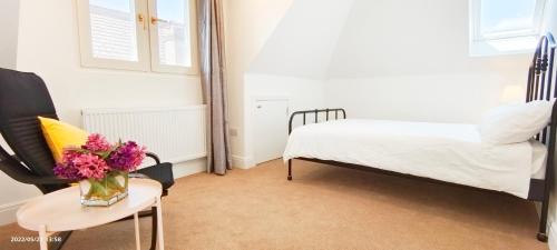 a bedroom with a bed and a table with a vase of flowers at Phlox Garden in Sutton