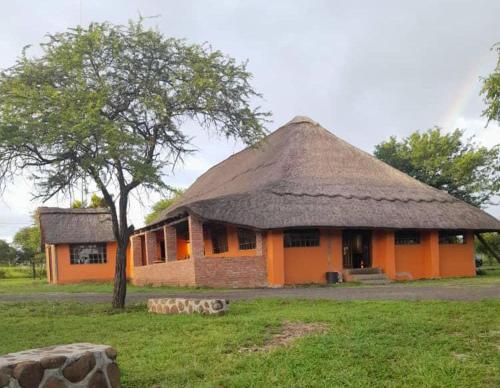 ein orangefarbenes Gebäude mit einem Strohdach und einem Baum in der Unterkunft Lituba Lodge 