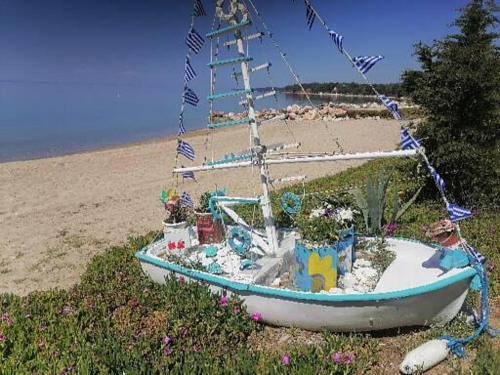 a boat sitting on the beach with flowers at Porto Almira Beachfront House in Nikiti