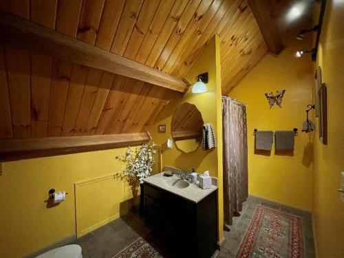 La salle de bains jaune est pourvue d'un lavabo et de toilettes. dans l'établissement Shadow Mountain Escape Cabin Rentals, à Luray