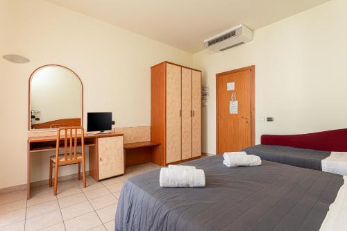 a bedroom with two beds and a desk and a mirror at HOTEL VILLA MARIA in Cesenatico