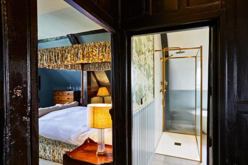 a bedroom with a bed and a lamp and a mirror at Ockenden Manor Hotel & Spa in Cuckfield