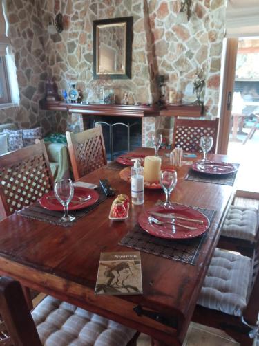 a wooden table with plates and wine glasses on it at Luxury Villas Chrysa Private Pool & Spa in Nafplio