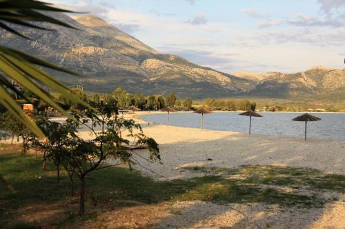 a beach with umbrellas and a mountain in the background at Asteri Apartments Mytikas 2-Bedroom Seaview Courtyard in Mýtikas