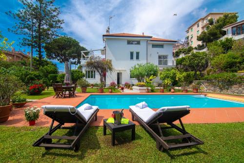 a swimming pool with two lounge chairs in front of a house at Magnificent Villa Sanremo in Sanremo